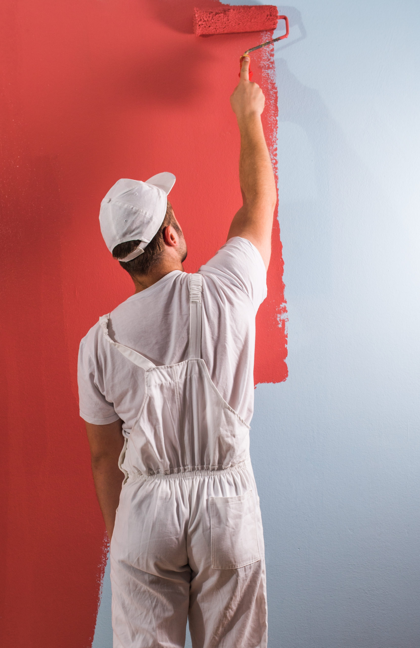 Peintre-en-train-de-repeindre-un-mur-en-rouge Peintre vu de dos en train de repeindre un mur blanc en rouge